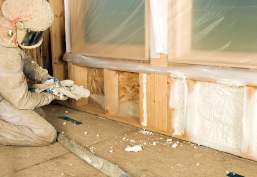 A full-geared contractor applying Spray Foam Insulation Stamford, CT for the wall system 
